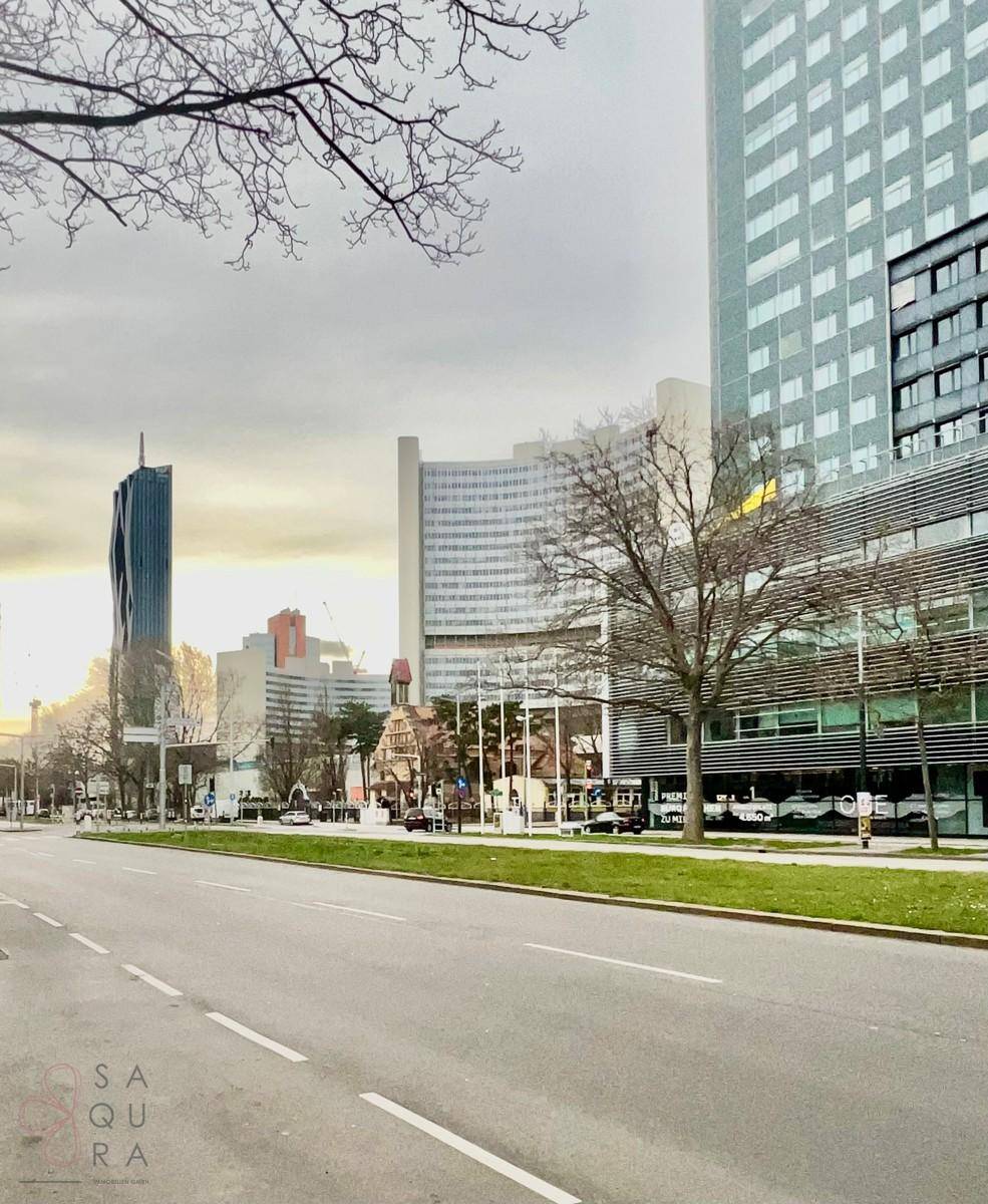 Stadtansicht mit modernen Hochhäusern und einer belebten Straße bei Dämmerung.