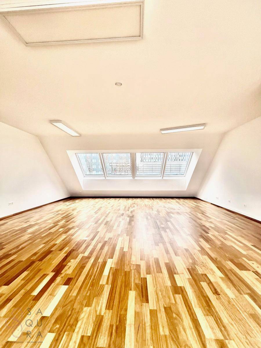Heller Raum mit Holzboden und großen Dachfenstern, ideal für verschiedene Nutzungen.
