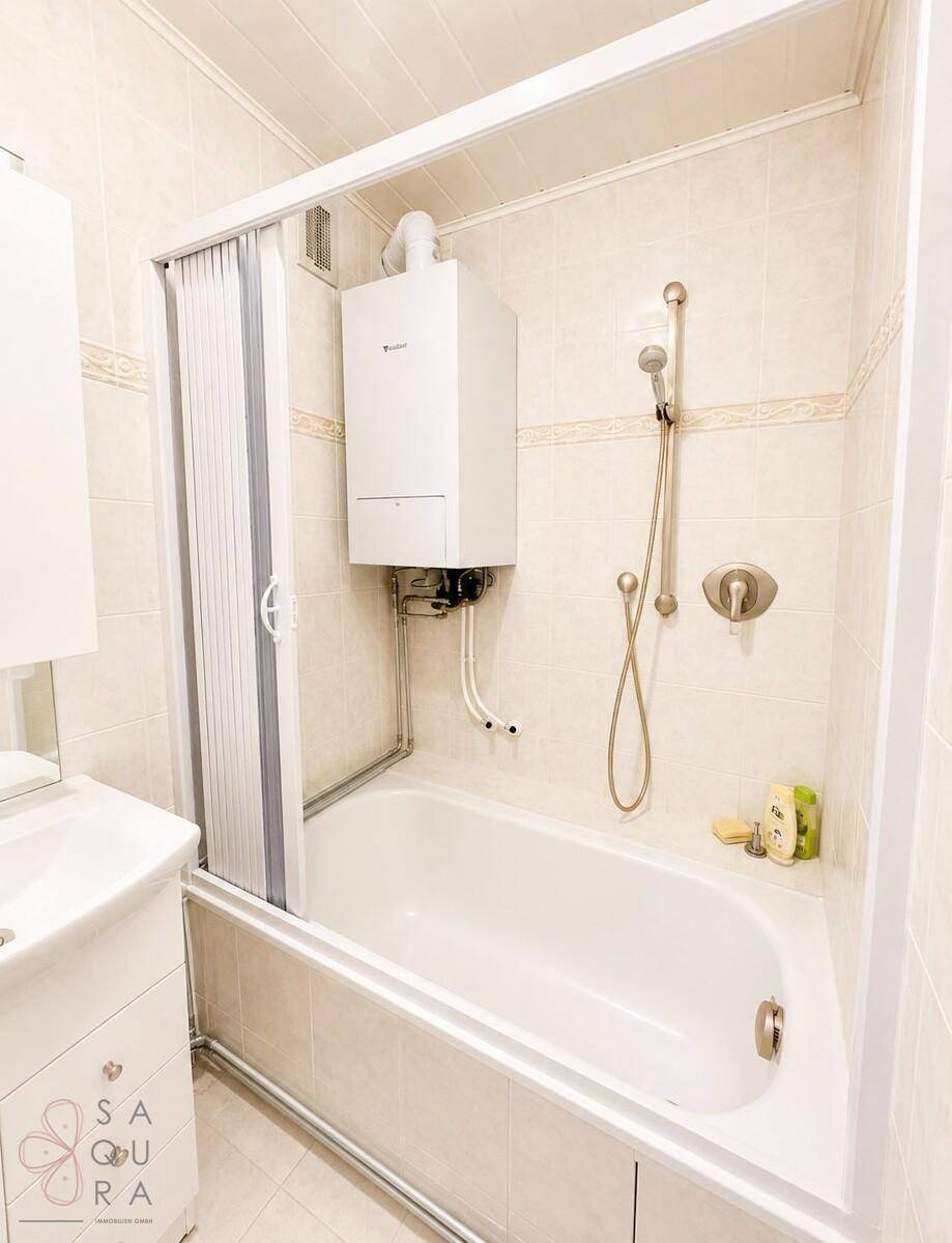 Badezimmer mit Badewanne, Duschvorrichtung und Wandheizgerät.