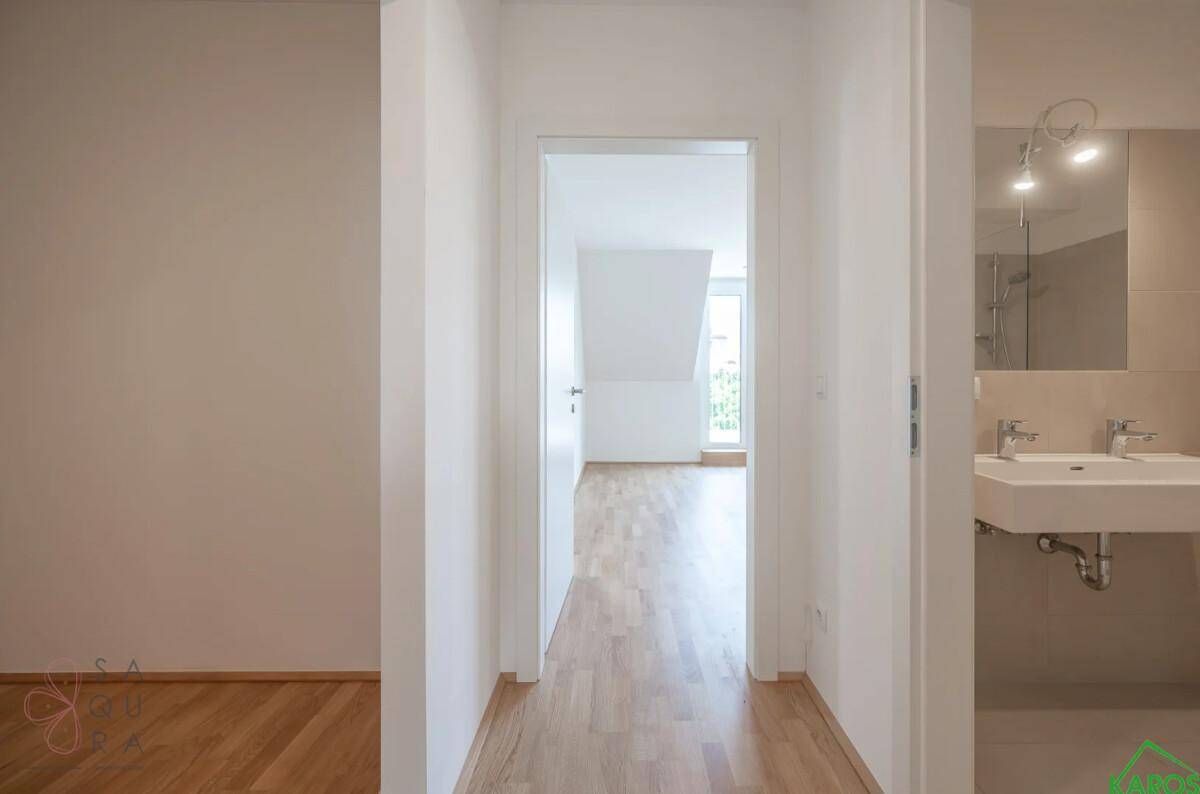 Heller Flur mit Parkettboden, der zu einem Badezimmer und einem weiteren Zimmer führt.