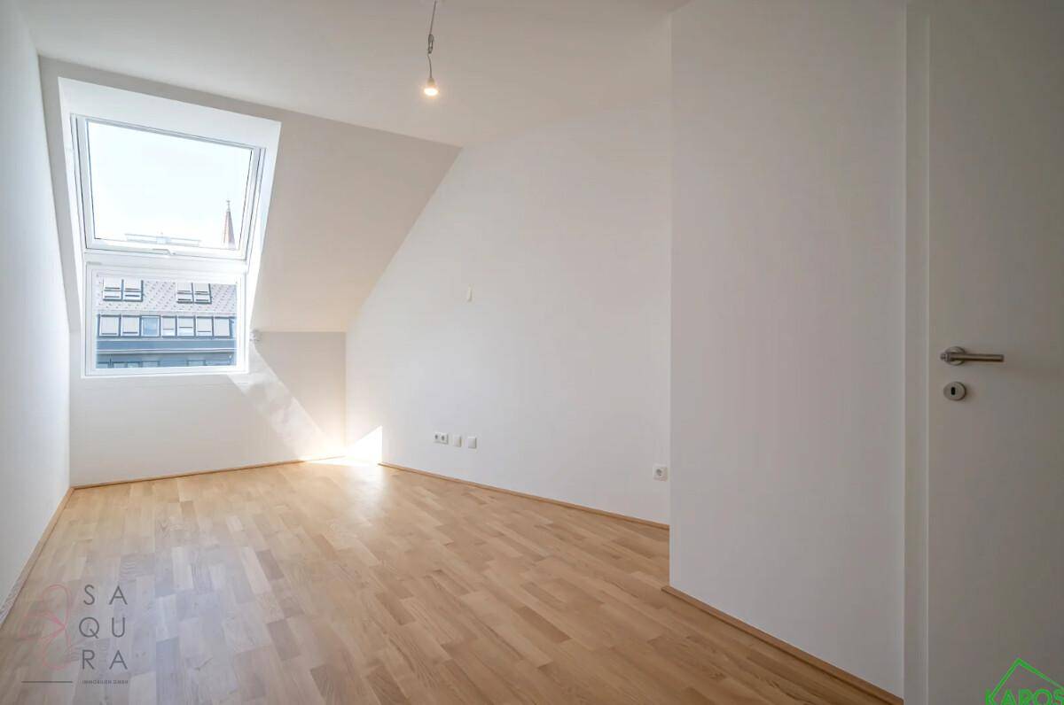 Helles Zimmer im Dachgeschoss mit großem Dachfenster und schrägen Wänden, ideal als Schlafzimmer.