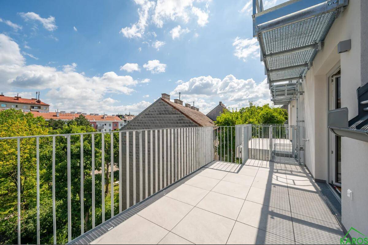 Geräumiger Balkon mit Fliesenboden und Metallgeländer, bietet einen Blick ins Grüne.