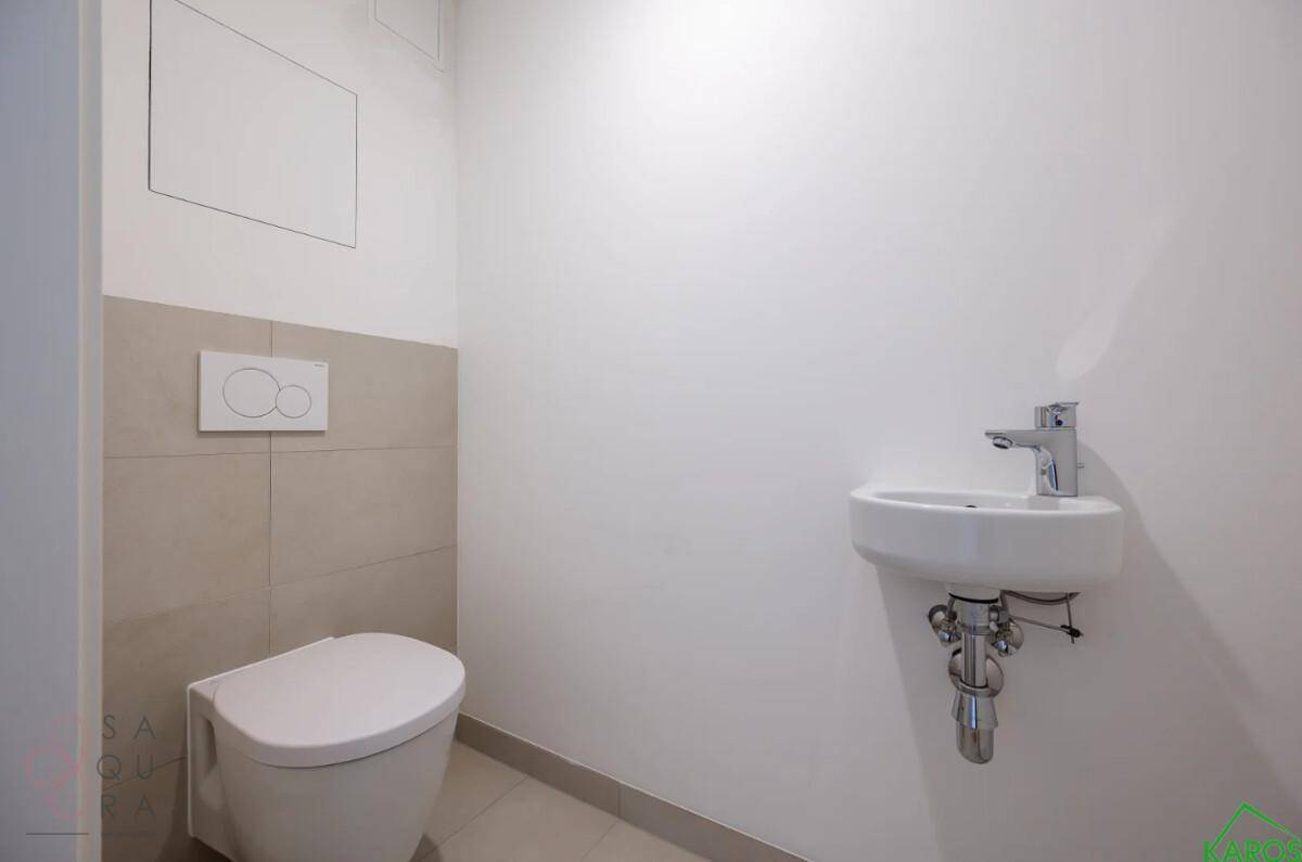 Modernes Gäste-WC mit wandhängender Toilette und kleinem Waschbecken, in hellen Farbtönen gehalten.
