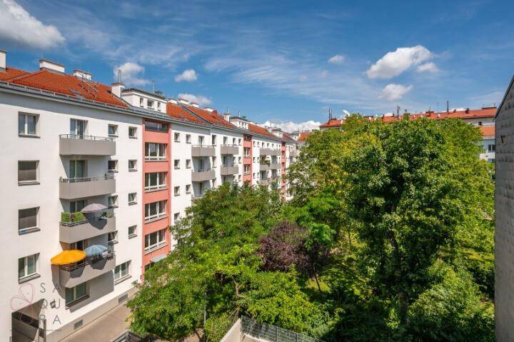 Blick auf eine Reihe von Wohngebäuden mit Balkonen, umgeben von üppigem Grün.