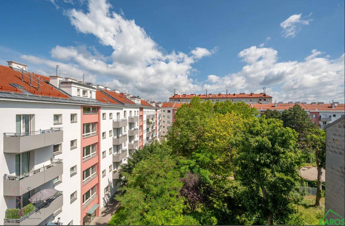 Panoramablick auf Wohngebäude mit Balkonen und einer grünen Umgebung unter blauem Himmel.