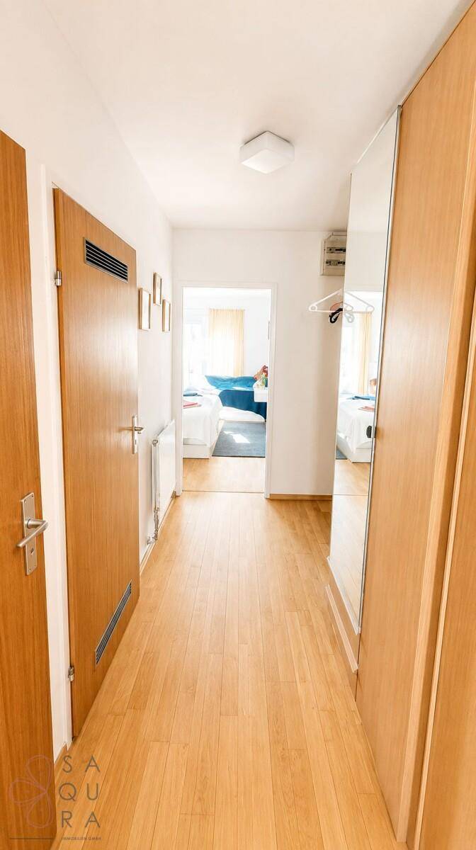 Langer Flur mit Holzboden und Spiegelschränken, der zu einem Schlafzimmer führt.