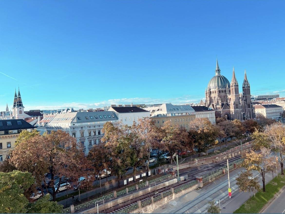 Beeindruckende Stadtansicht mit einer großen Kirche und herbstlichen Bäumen im Vordergrund.