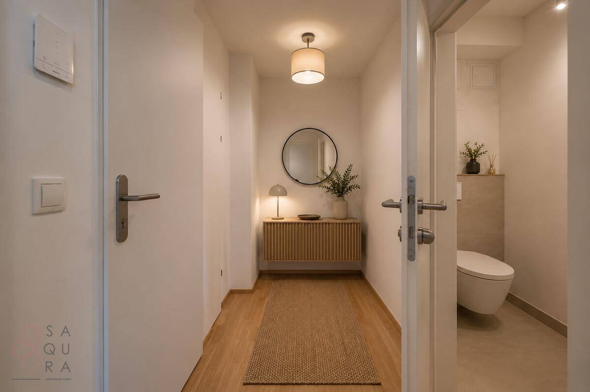 Modern eingerichteter Flur mit Holzboden, Spiegel und Zugang zum Gäste-WC.