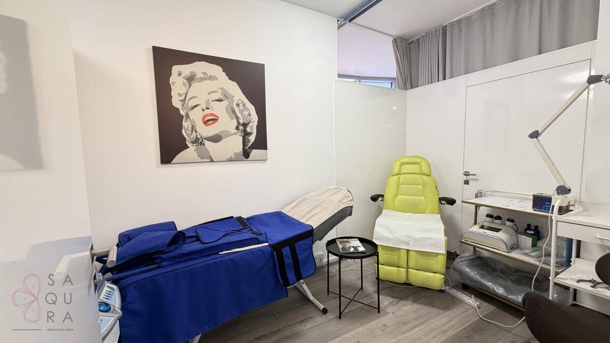 Behandlungsraum mit Spezialliege, Geräten und einem Pop-Art-Bild von Marilyn Monroe an der Wand.