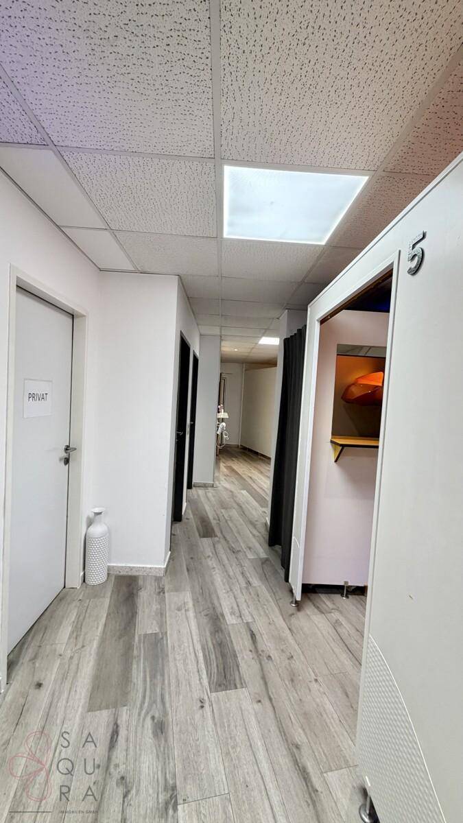Heller Flur mit Laminatboden und mehreren Türen, die zu den einzelnen Kabinen führen.
