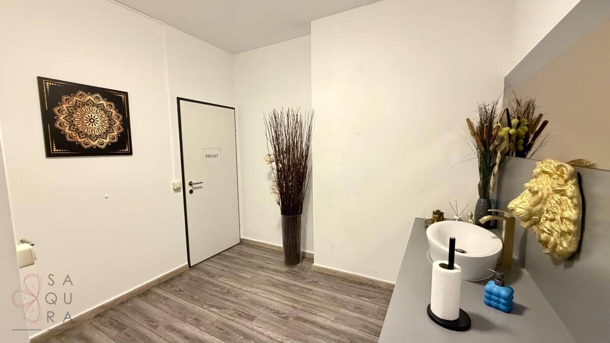 Waschbereich mit modernem Waschbecken, dekorativem Spiegel und einer Tür zum Privatbereich.