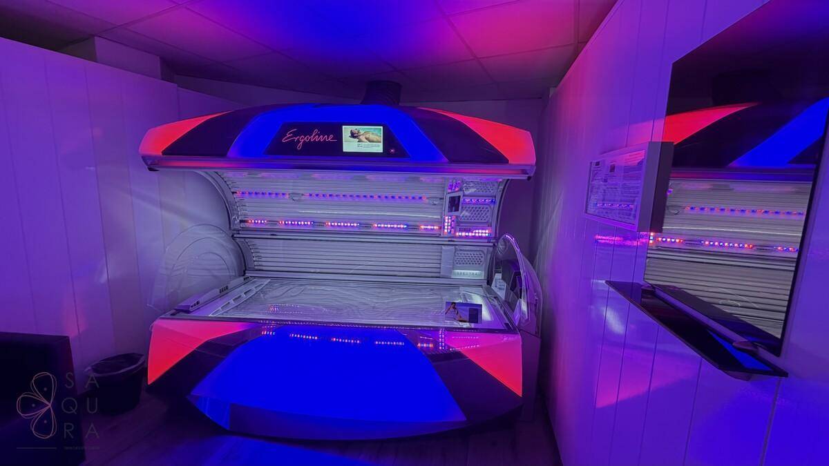 Solariumkabine mit dynamischer blau-roter Beleuchtung und modernem Bräunungsgerät für ein einzigartiges Ambiente.