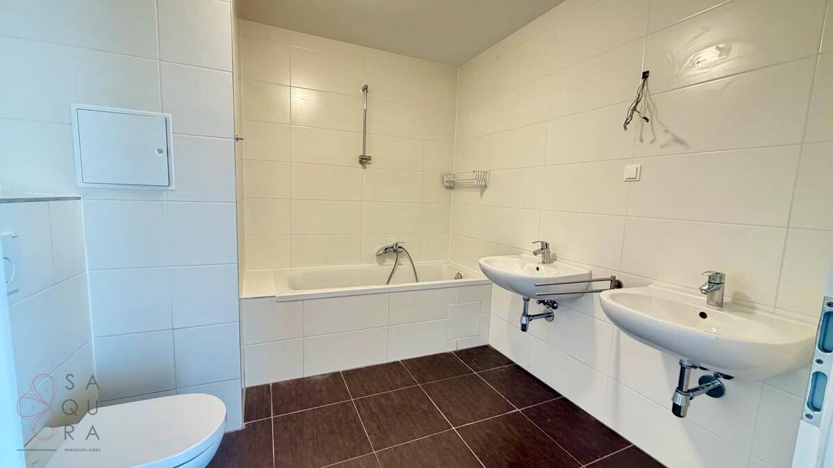Geräumiges Badezimmer mit Badewanne, Dusche, Toilette und Doppelwaschbecken, komplett gefliest.