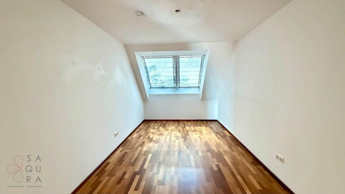 Gemütliches Zimmer mit Holzboden und Dachfenstern, das eine helle Atmosphäre schafft.