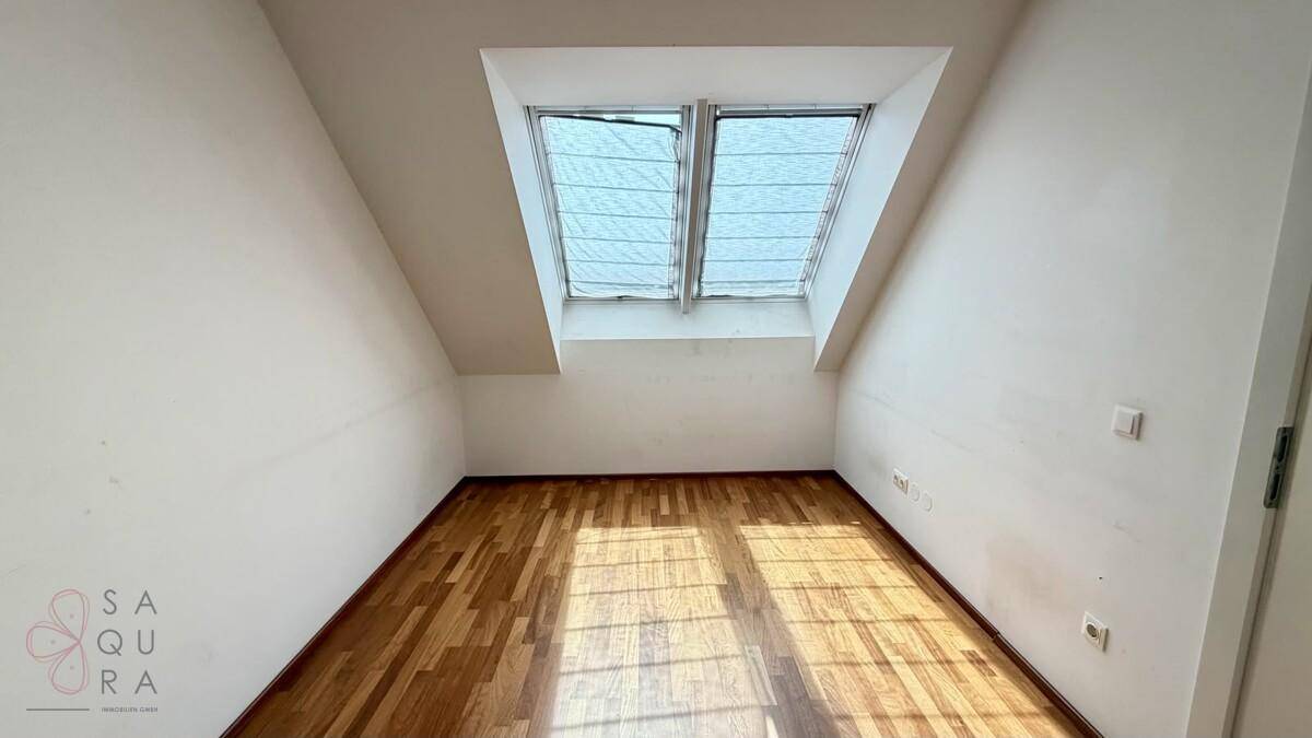 Helles Schlafzimmer mit Holzboden und zwei Dachfenstern, ideal für natürliches Licht.