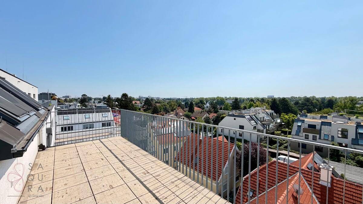 Große Dachterrasse mit Fliesenboden und Metallgeländer, bietet einen weiten Blick über die Stadt.