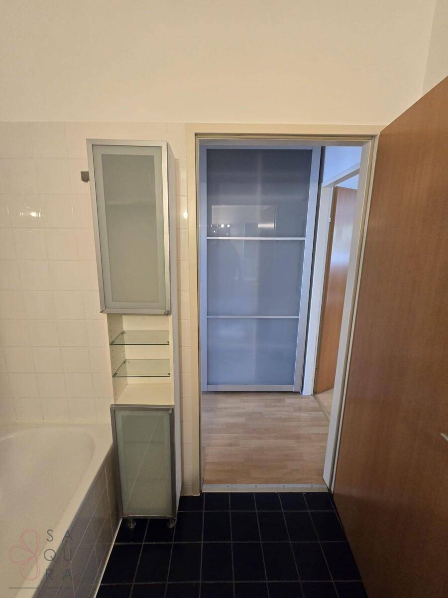 Badezimmer mit Badewanne und praktischem Hochschrank, angrenzend an den Flur.