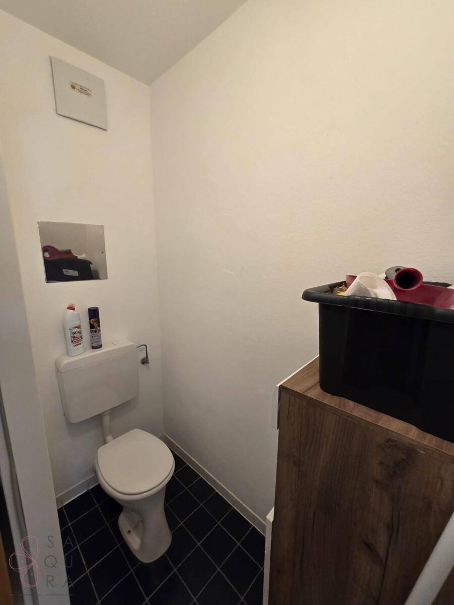 Separates Gäste-WC mit Toilette und kleinem Stauraum, in schlichtem Design.