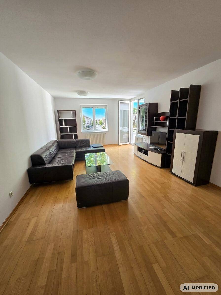 Geräumiges Wohnzimmer mit dunklem Ledersofa, modernem TV-Möbel und hellem Holzfußboden.