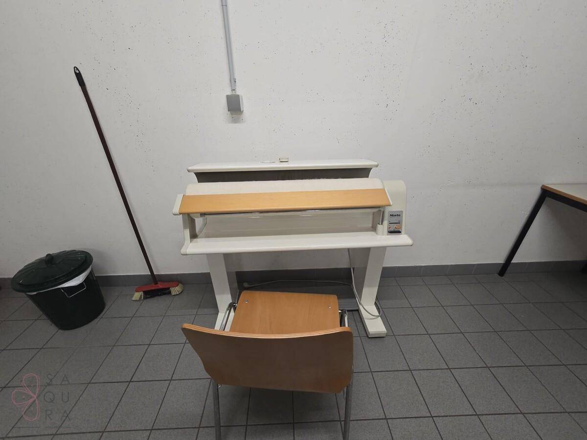 Gemeinschaftlicher Waschraum mit Bügelmaschine und Stuhl, zur Nutzung für die Hausgemeinschaft.