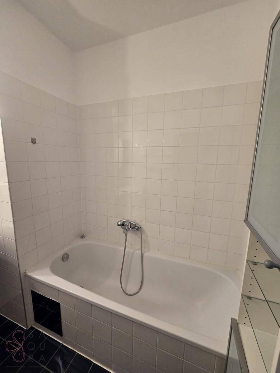 Nahaufnahme der Badewanne im gefliesten Badezimmer, in gutem und gepflegtem Zustand.