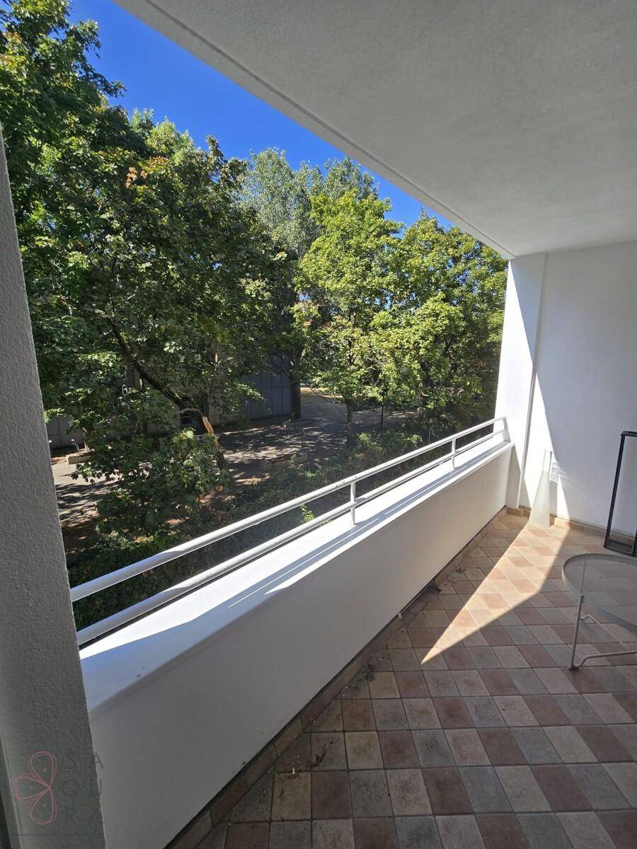 Ruhiger Balkon mit Fliesenboden und angenehmem Blick ins Grüne mit altem Baumbestand.