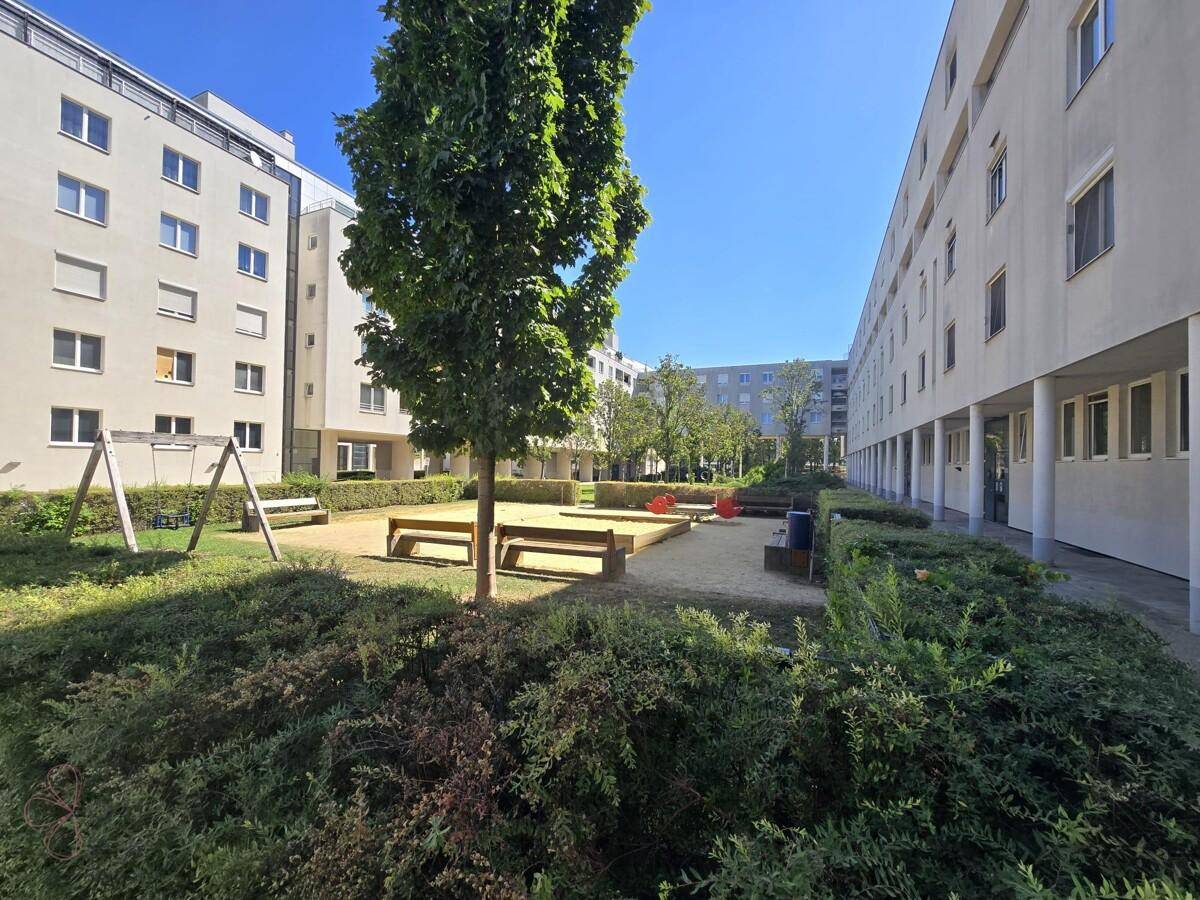 Außenansicht des Gebäudekomplexes mit Innenhof, Spielplatz und gepflegten Grünflächen.
