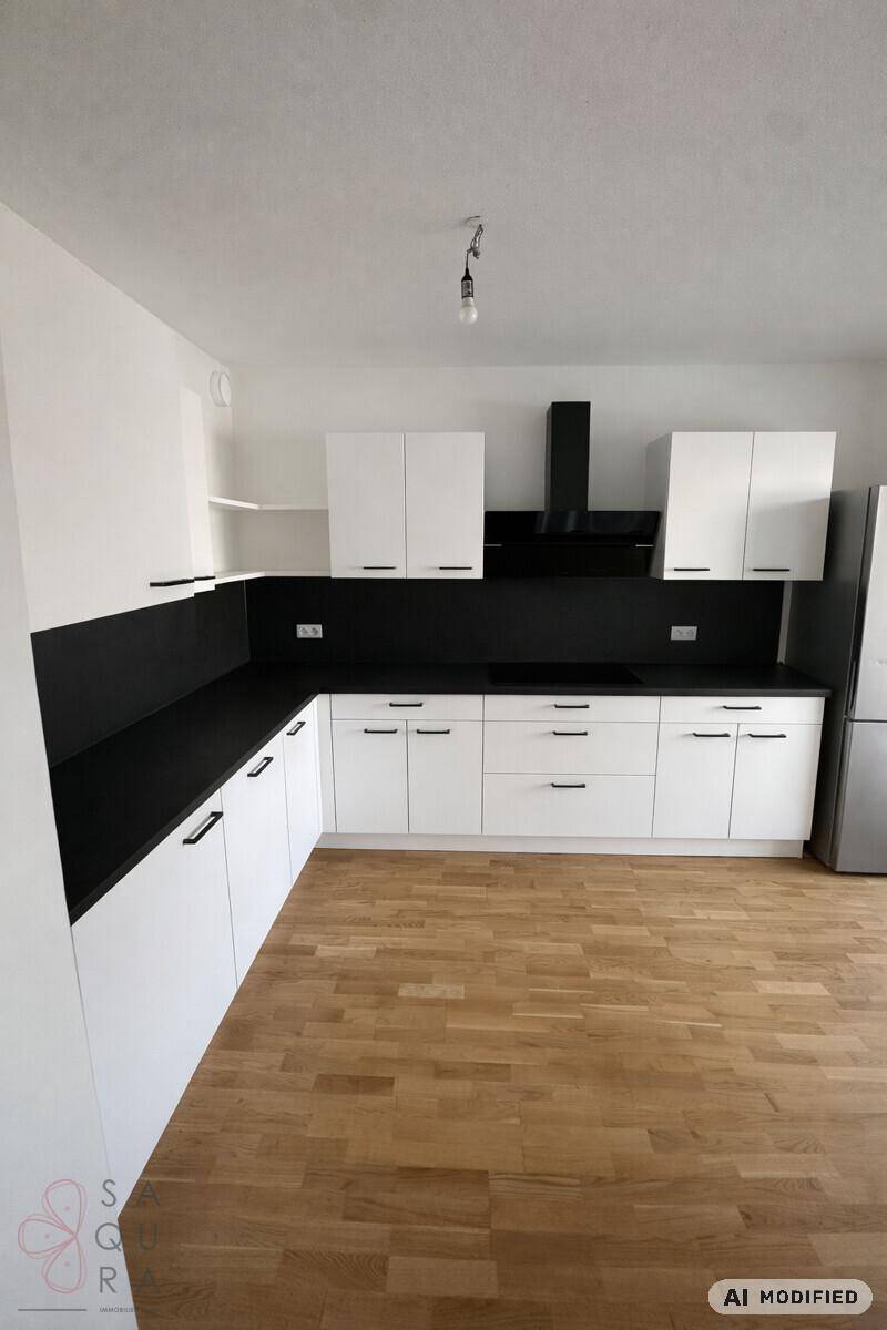 Moderne Küche mit weißen Schränken, schwarzen Arbeitsplatten und Holzboden.