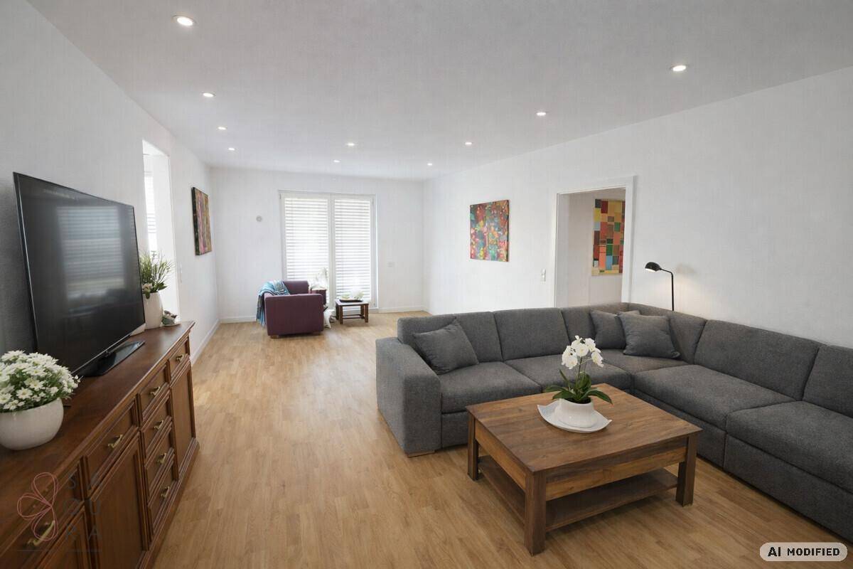 Geräumiges Wohnzimmer mit modernem Ecksofa, Holzboden und integrierten Deckenleuchten.
