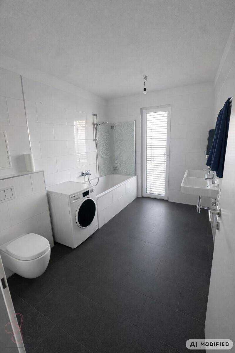 Modernes Badezimmer mit Badewanne, Dusche, Doppelwaschbecken und Waschmaschine.