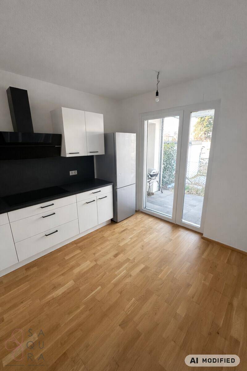 Helle Küche mit Zugang zu einem Außenbereich durch eine große Glastür.