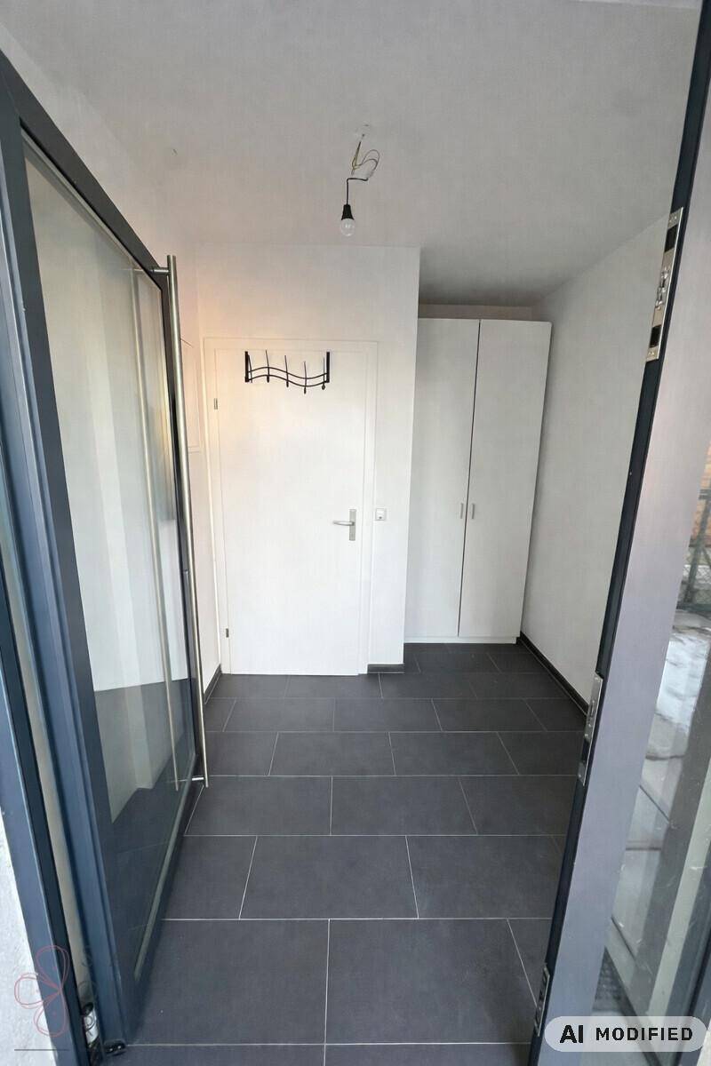 Eingangsbereich mit Fliesenboden, Garderobe und Zugang zum Außenbereich durch eine Glastür.