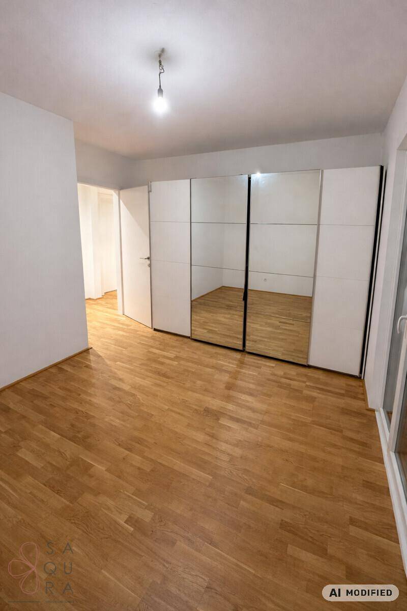 Schlafzimmer mit Holzboden und einem großen Spiegelschrank, der den Raum optisch vergrößert.