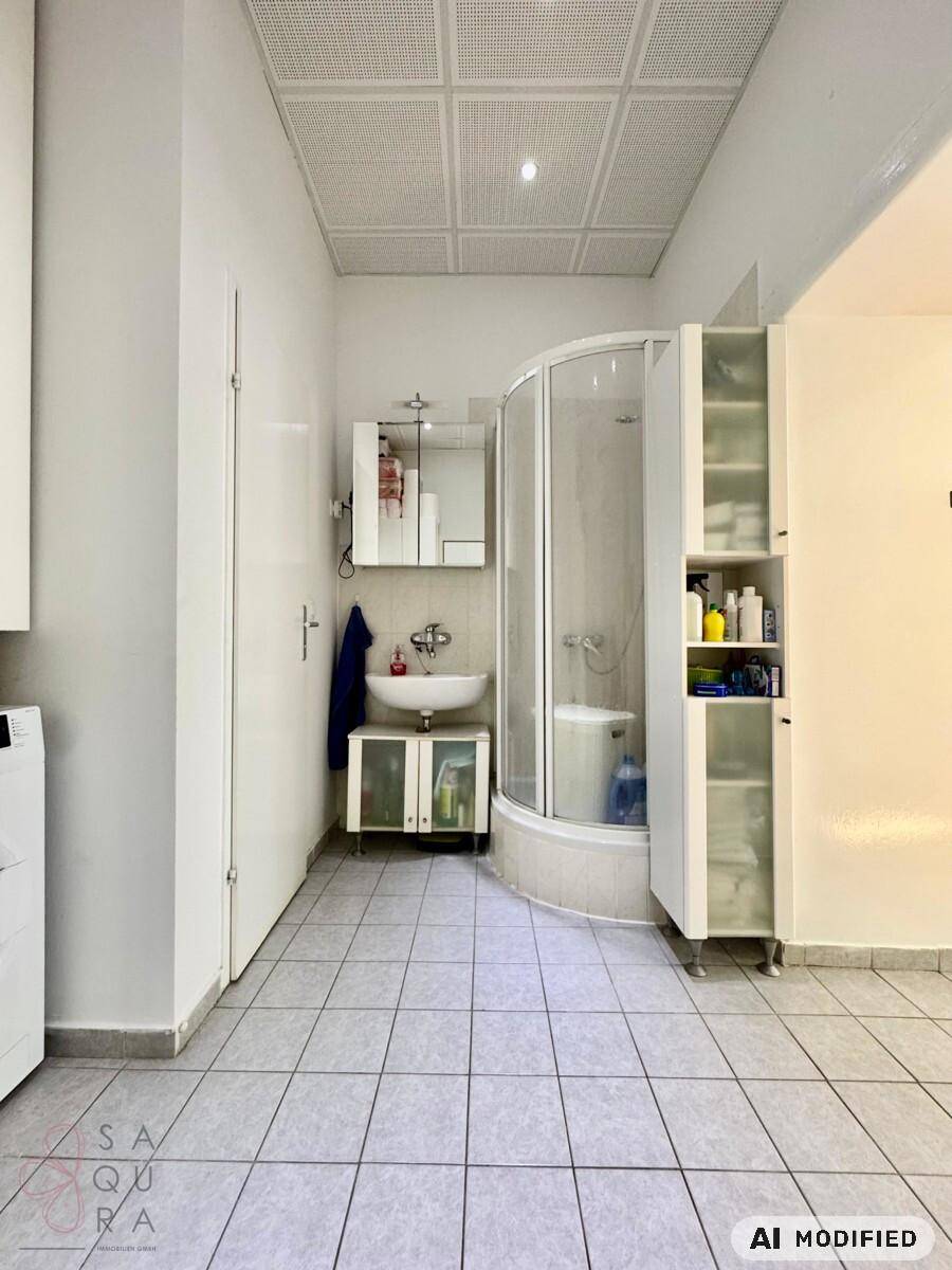Badezimmer mit Duschkabine, Waschbecken und Fliesenboden.