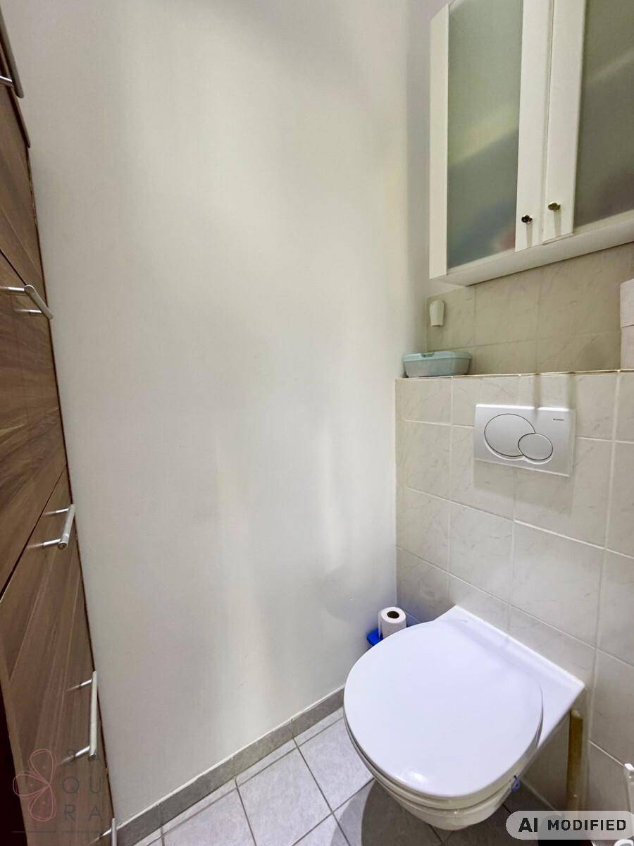 Separate Toilette mit Wand-WC und hellen Fliesen an Wänden und Boden.