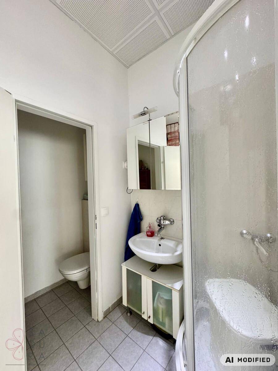 Badezimmer mit Duschkabine, Waschbecken und Zugang zu einer separaten Toilette.