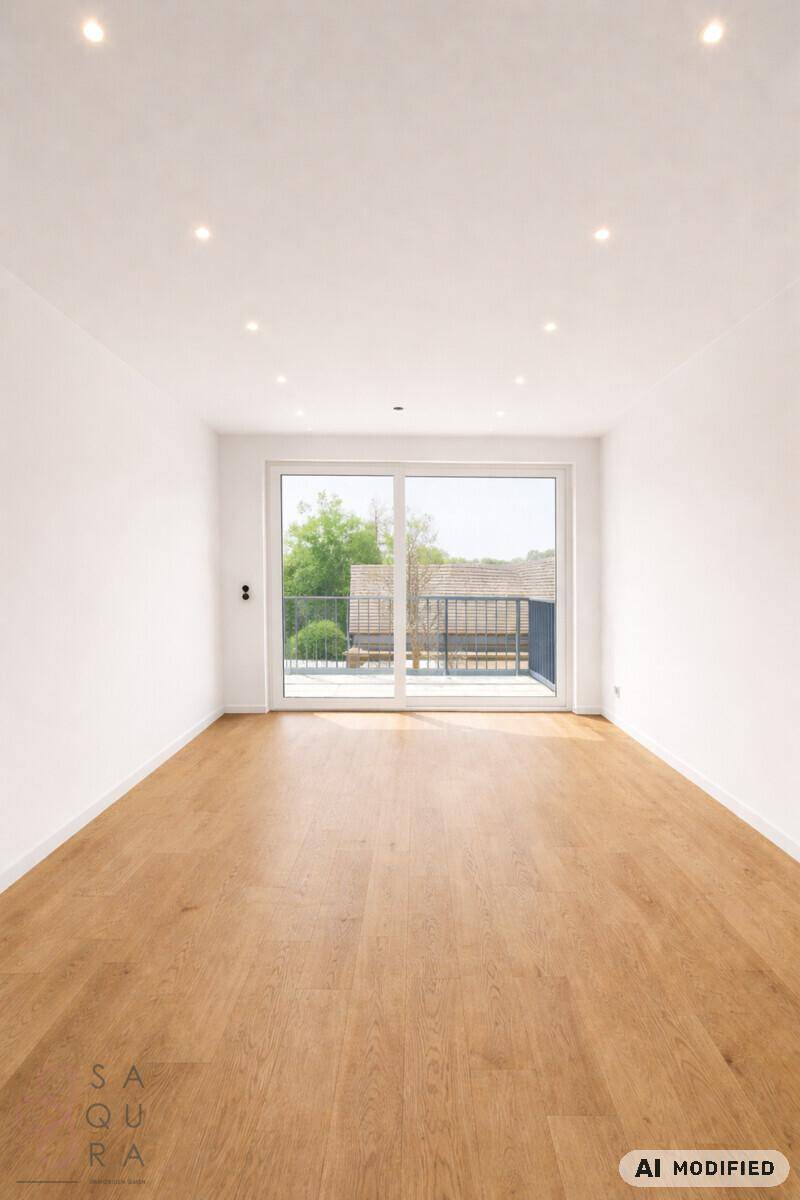 Heller, leerer Raum mit Holzboden und großen Fenstern, die Zugang zu einem Balkon bieten.
