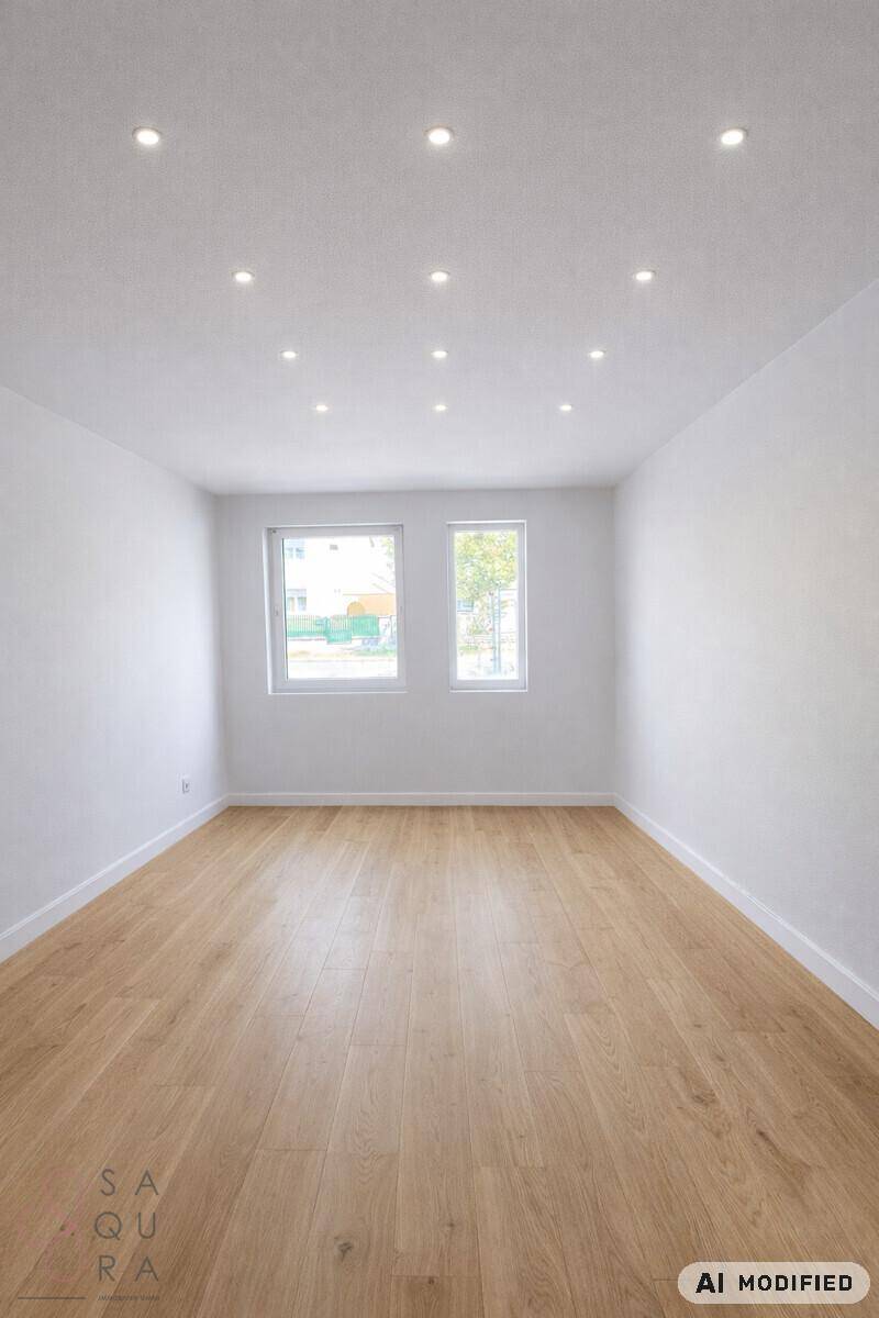 Heller, leerer Raum mit Holzboden und zwei Fenstern für optimale Belichtung.