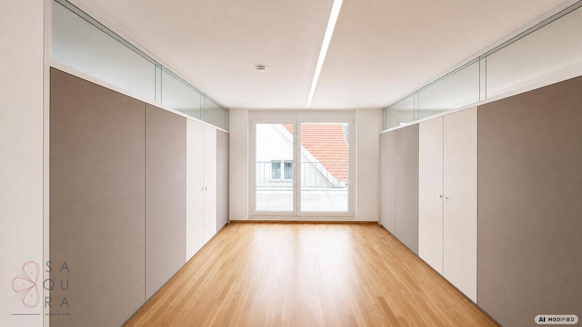 Leerer Raum mit Holzboden und großen Fenstern, die viel Tageslicht hereinlassen.