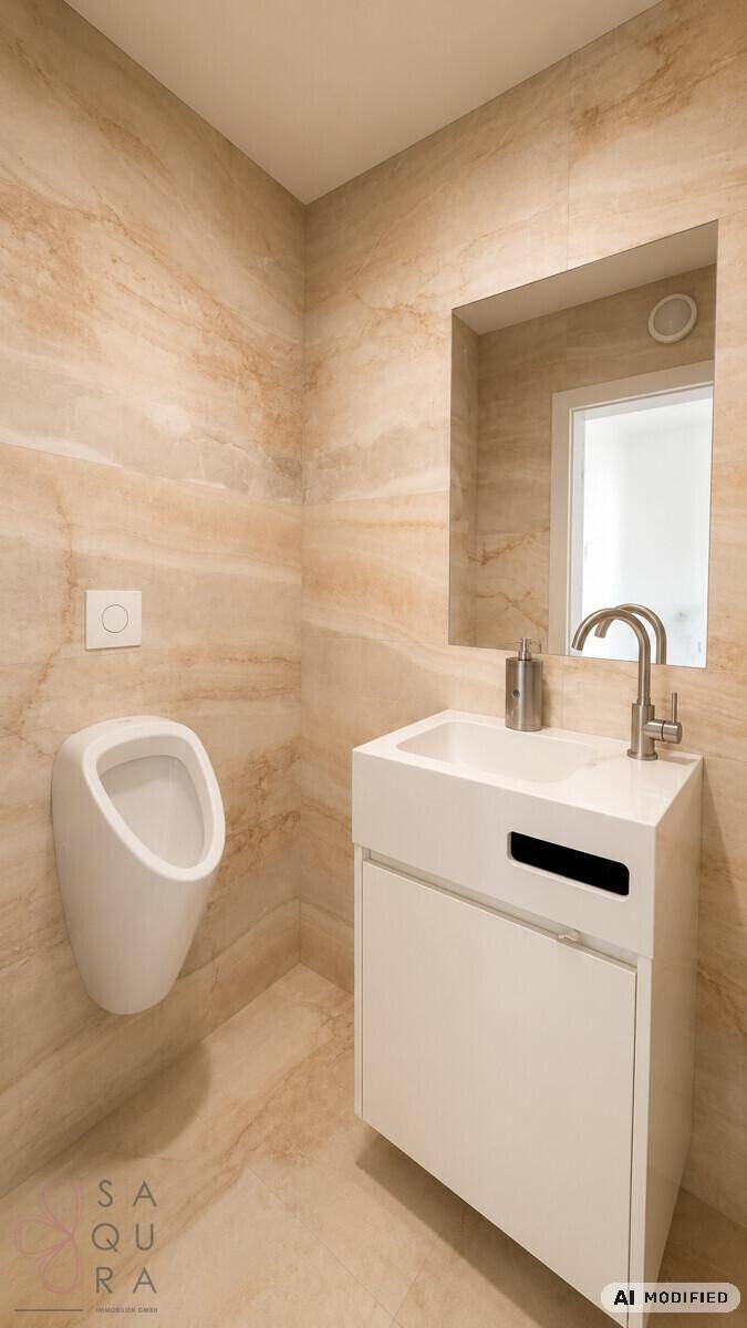Modernes Badezimmer mit Urinal, Waschbecken und eleganten Marmorfliesen an den Wänden.