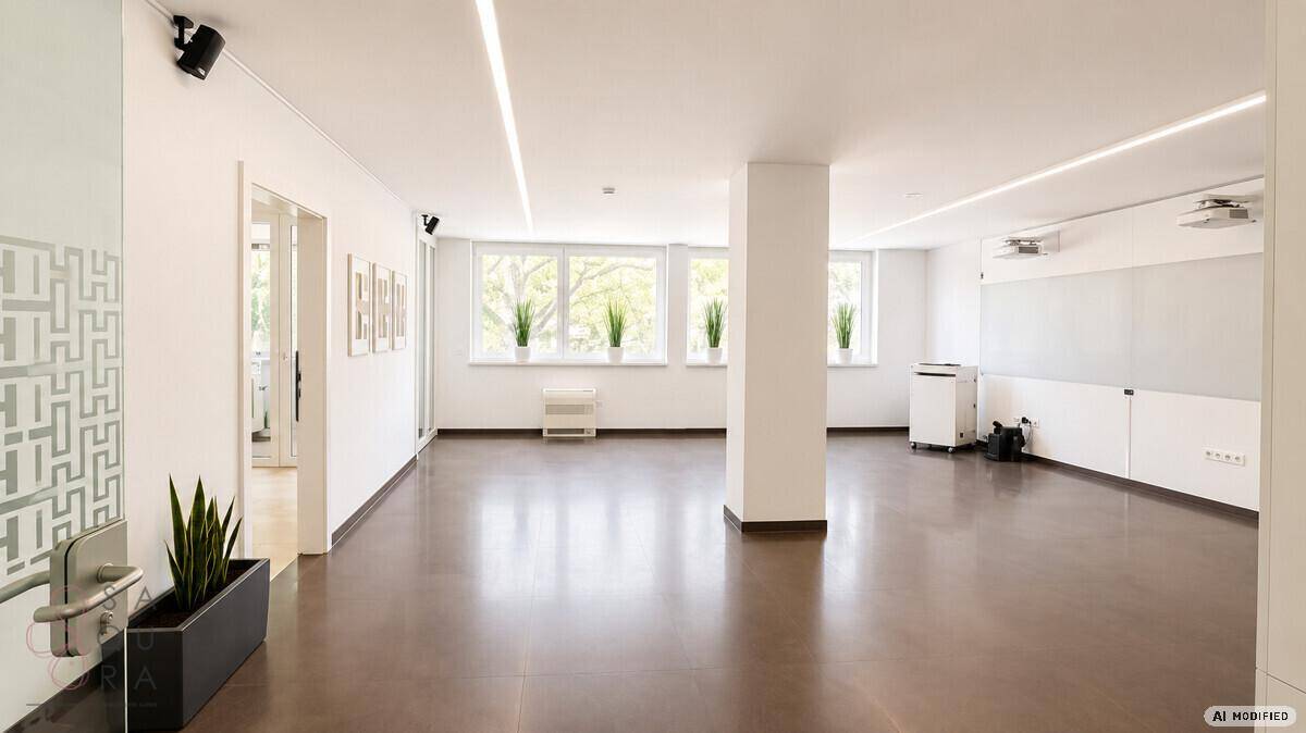 Großer, offener Büroraum mit dunklem Boden, Säulen und vielen Fenstern für natürliches Licht.
