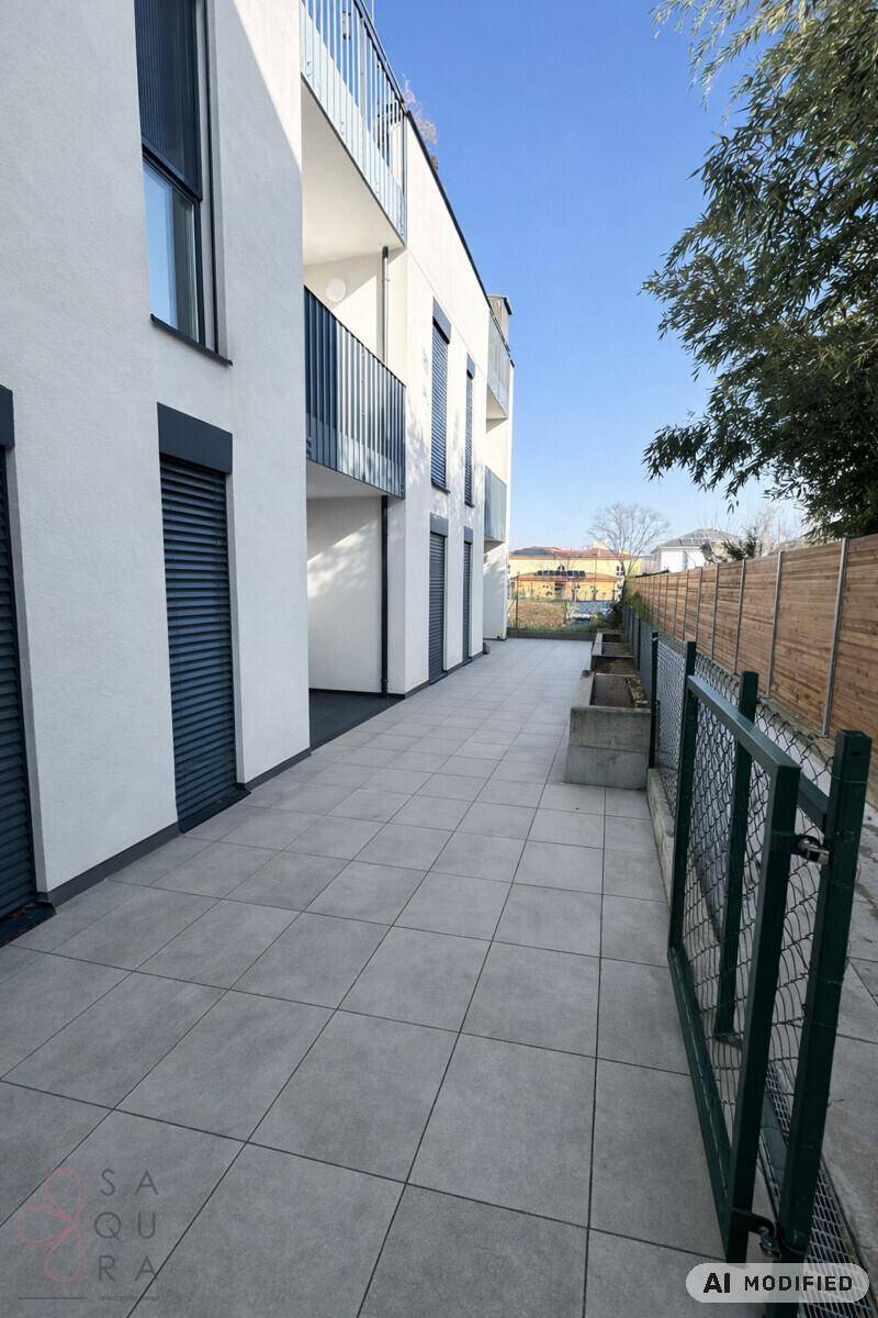 Moderne Gebäudefassade mit einer gepflasterten Terrasse und dunklen Fensterläden unter blauem Himmel.