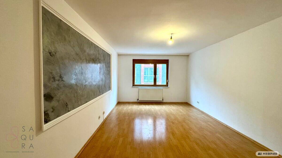Heller Wohnraum mit Parkettboden, weißen Wänden und einem Fenster mit grünen Fensterläden.