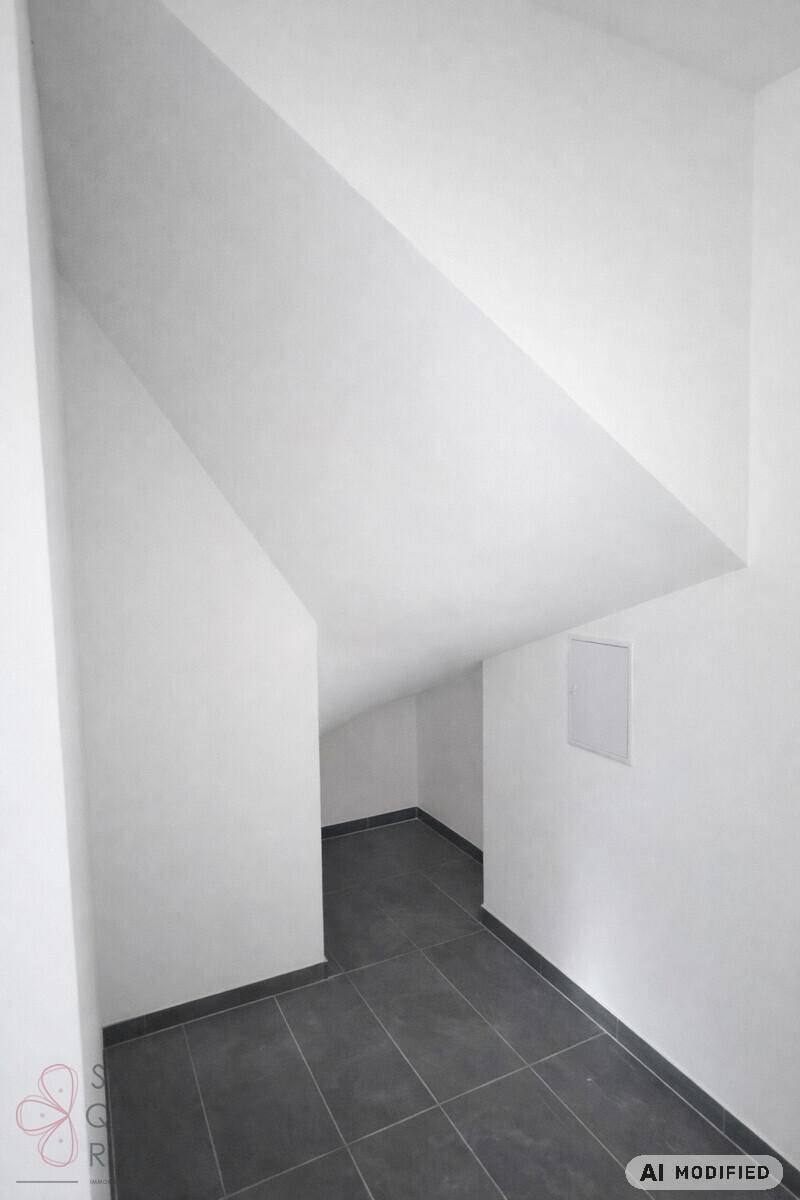 Abstellraum mit dunklem Fliesenboden und schrägen Wänden unter dem Dach.