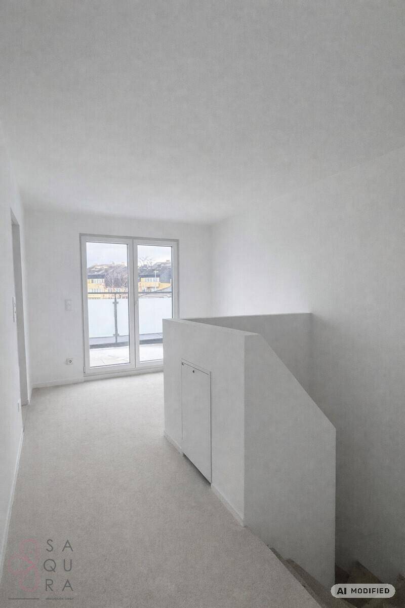 Heller Flur mit Zugang zu einem Balkon und Treppenaufgang in einem Neubau.