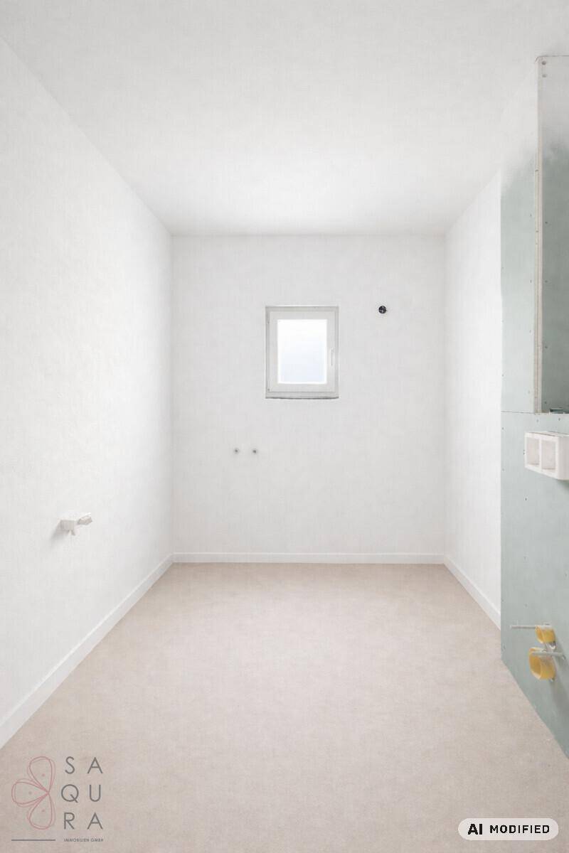 Heller, unmöblierter Raum mit Fenster und vorbereiteten Anschlüssen für ein Badezimmer.