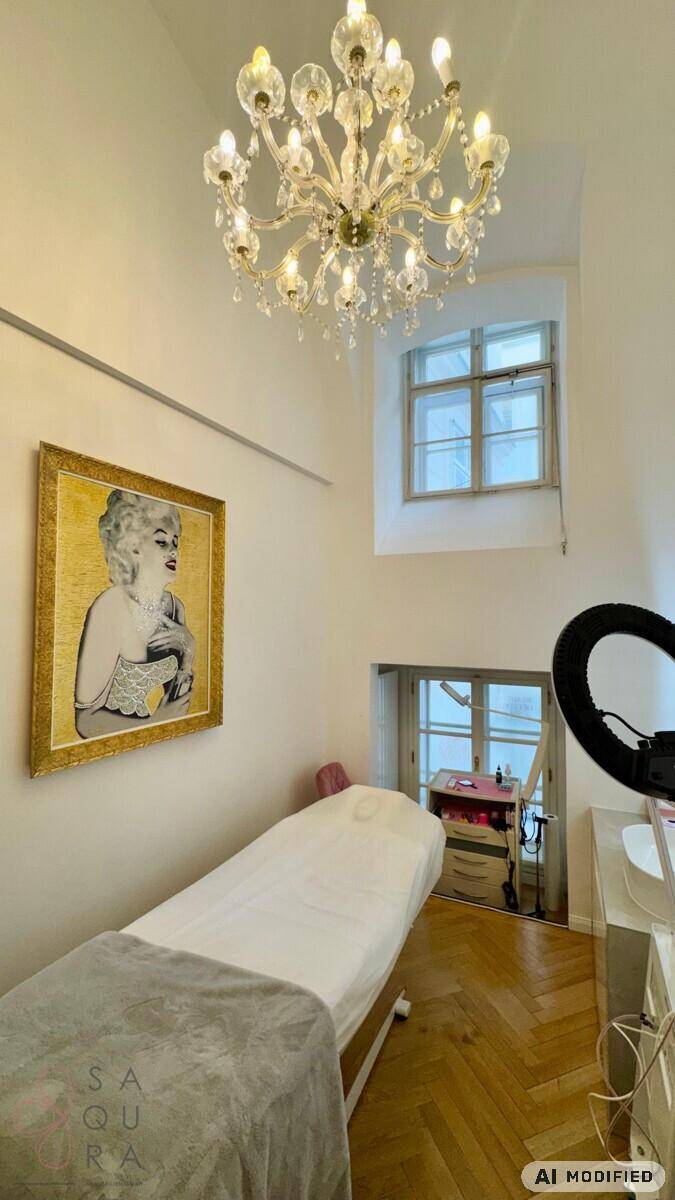 Behandlungsraum mit Liege, Kronleuchter und hohem Fenster, dekoriert mit einem Wandbild und Parkettboden.
