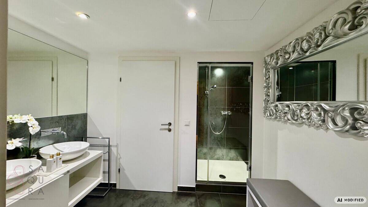 Modernes Badezimmer mit Doppelwaschbecken, großem Spiegel, dunklen Fliesen und einer Glasdusche.
