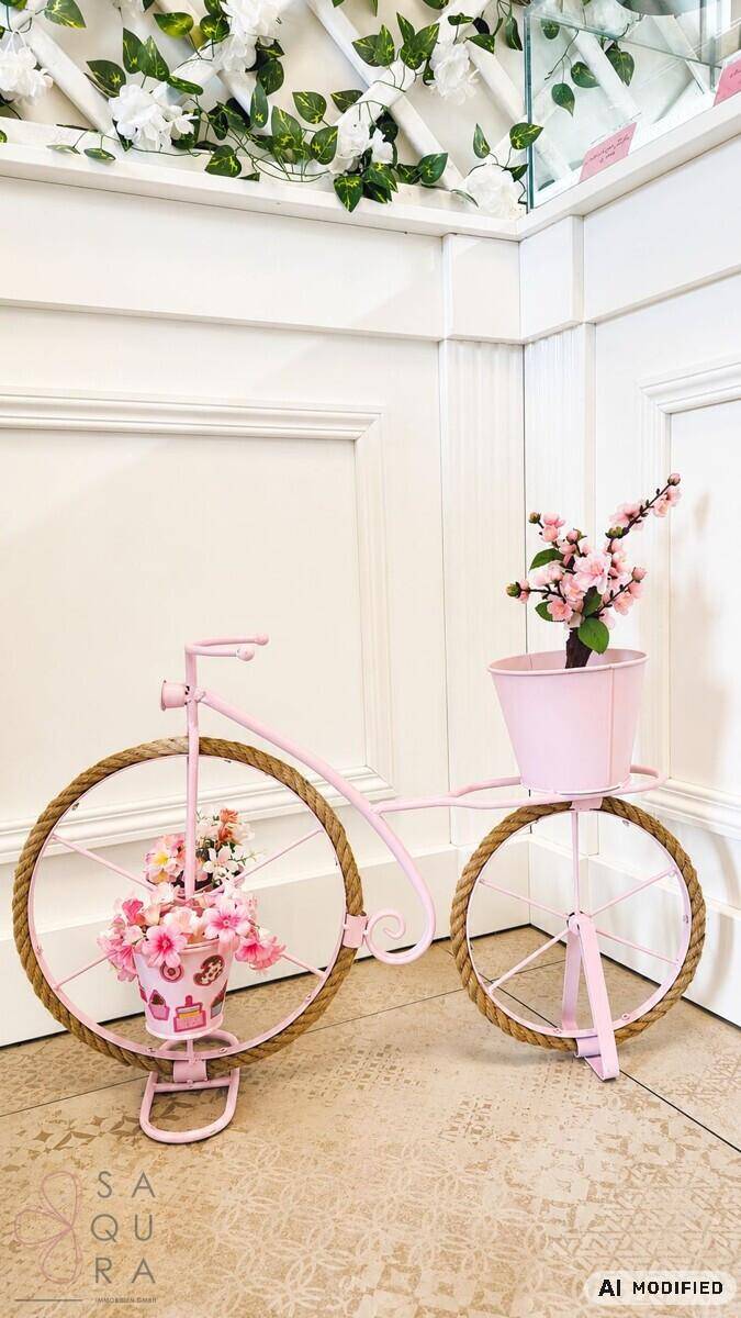 Ein charmantes rosa Dekofahrrad mit Blumenarrangements auf dem gefliesten Boden.