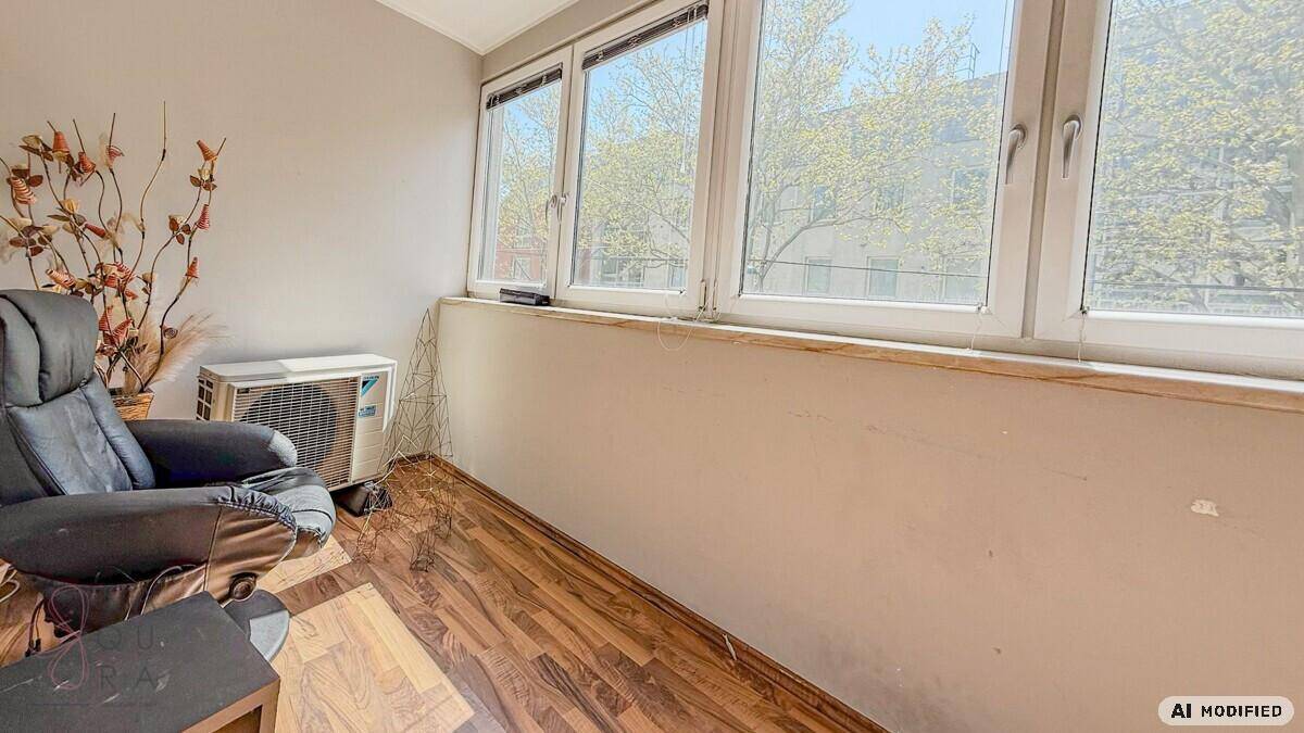 Heller Wintergarten oder verglaster Balkon mit Sessel und Klimaanlage, ideal zum Entspannen.